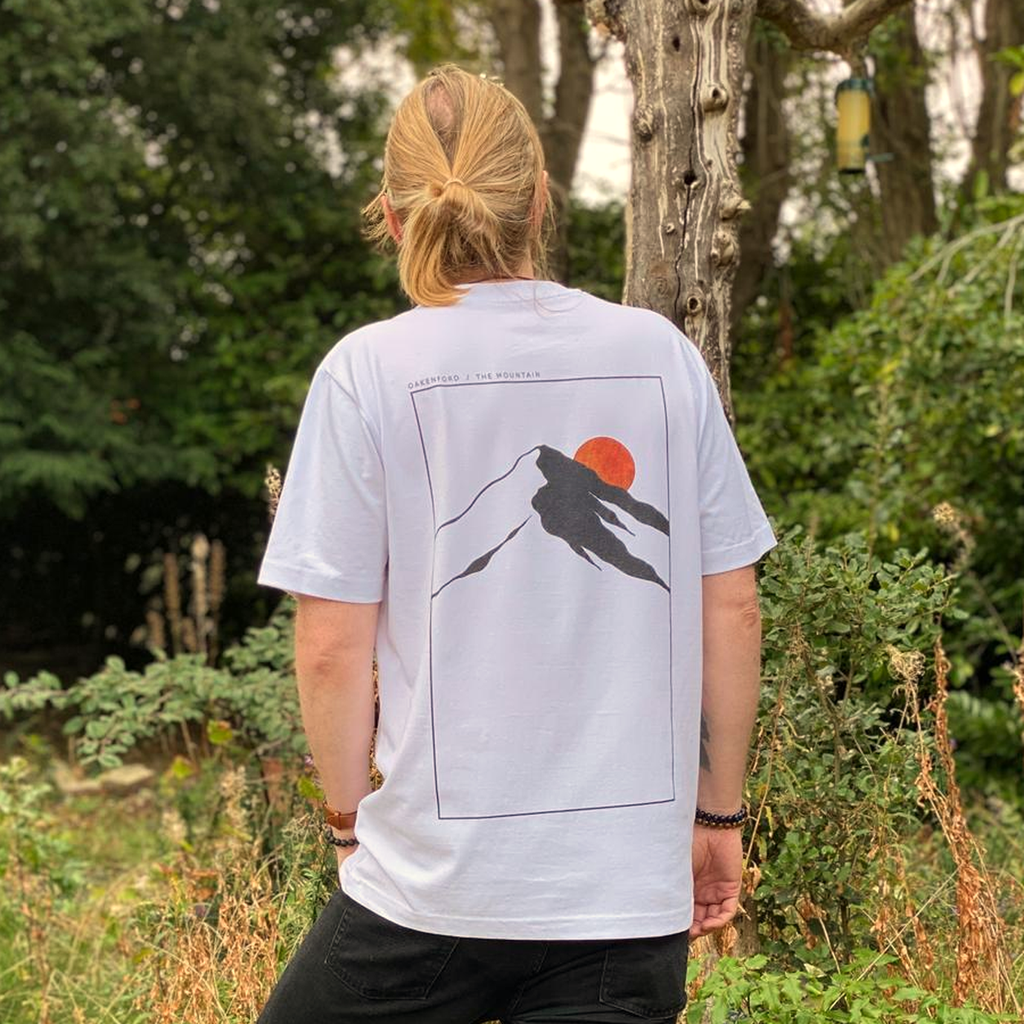 Model wearing the white Mountain Oakenford graphic T-shirt, showing the full back and hem