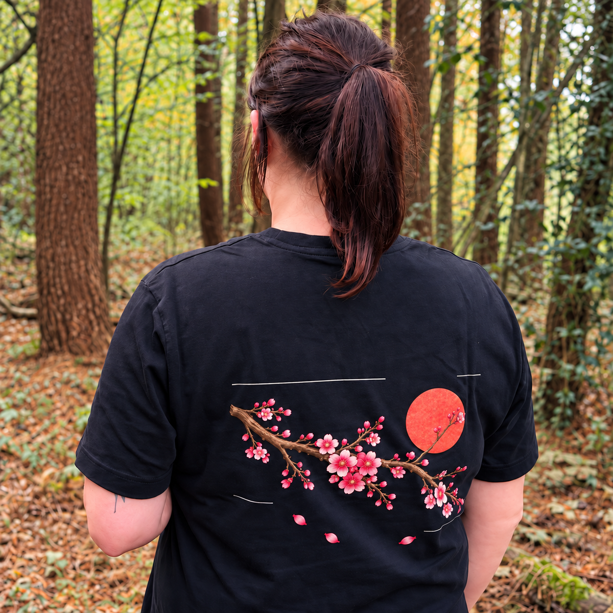 Cherry Drift black T-shirt worn in woodland, showing the cherry blossom back print