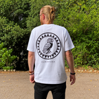 Standing model wearing the white Owl Shield Oakenford graphic T-shirt, back view