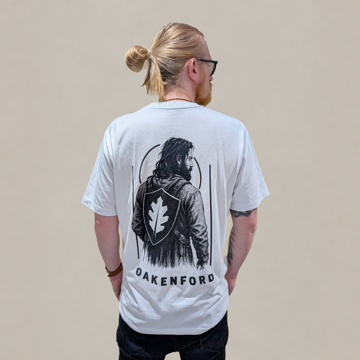Model wearing the white Shield Bearer T-shirt, looking right and showing the back print.