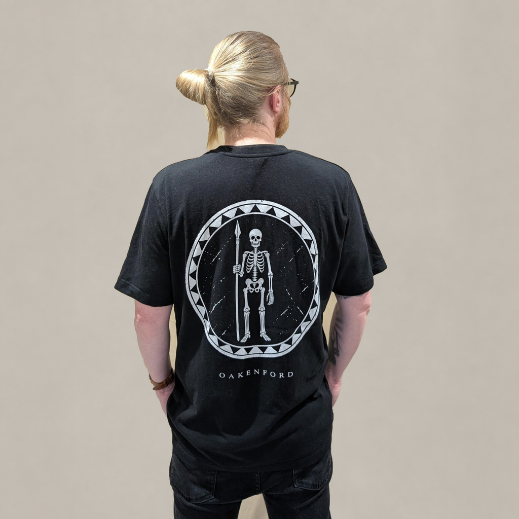 Model wearing the black Skeleton Shield T-shirt, showing the back print.
