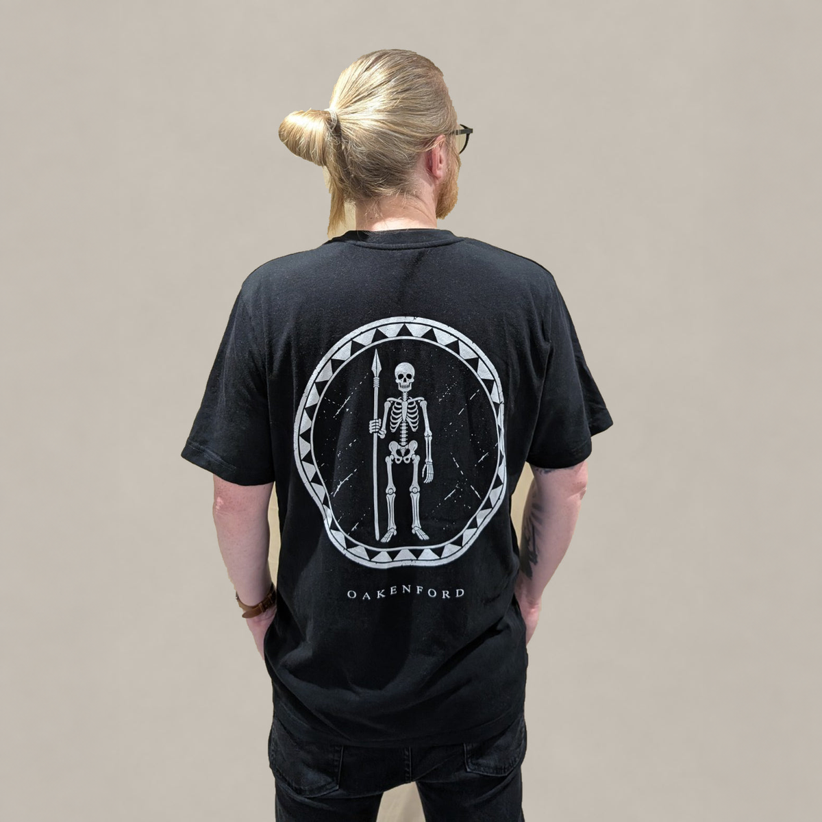Model wearing the black Skeleton Shield T-shirt, showing the back print.