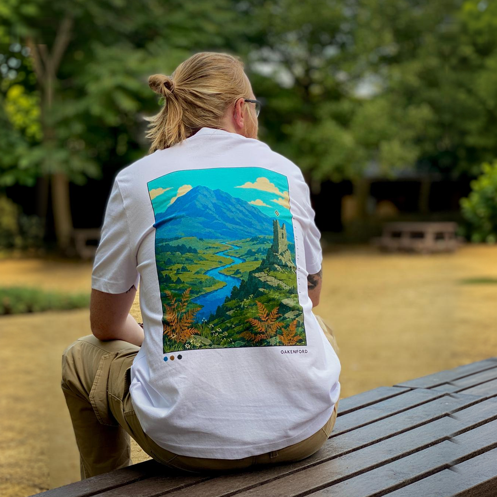 Seated model wearing The Overlook white Oakenford T-shirt, showing the full head and back artwork