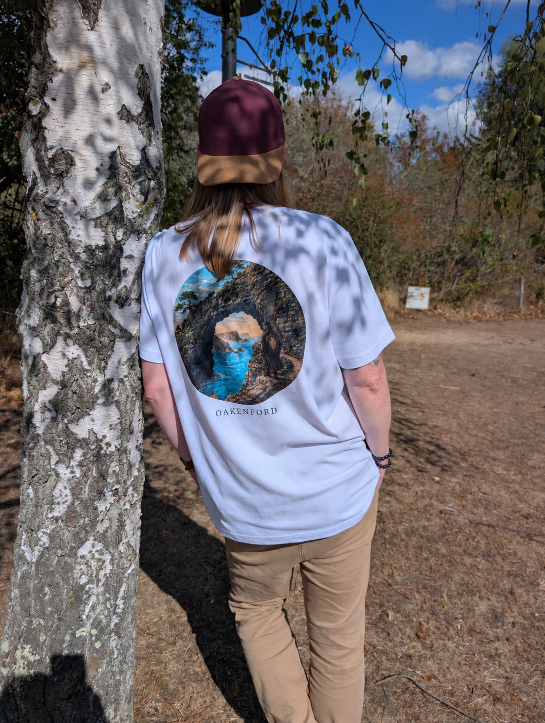 Stone Current white tee worn beside a birch tree, with a plain cap